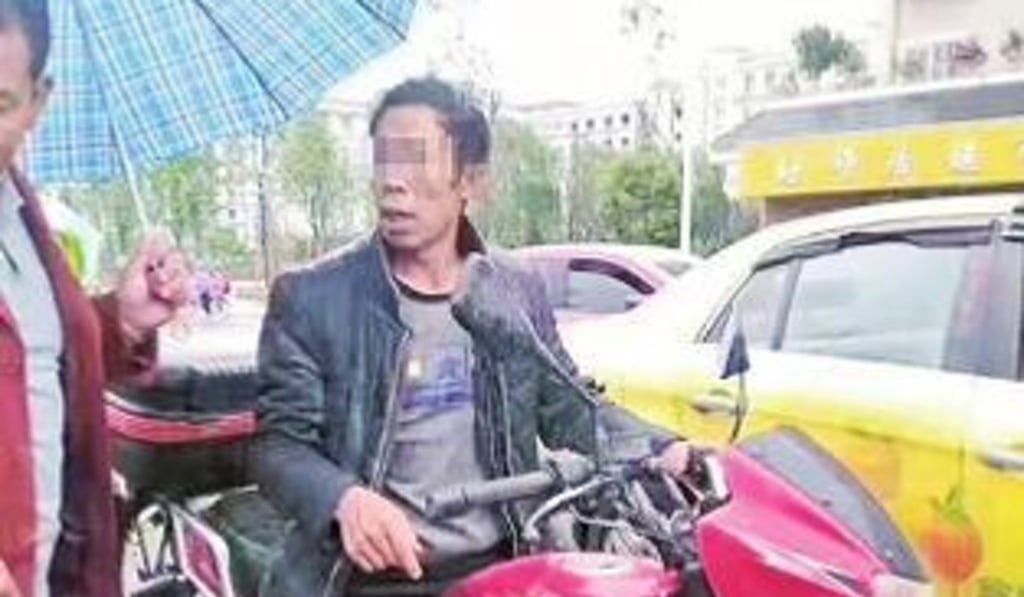 A member of the public talks to the boy’s father as he sits on his motorbike. An angry crowd ordered the dad to give his jacket to his shivering son. Photo: Handout