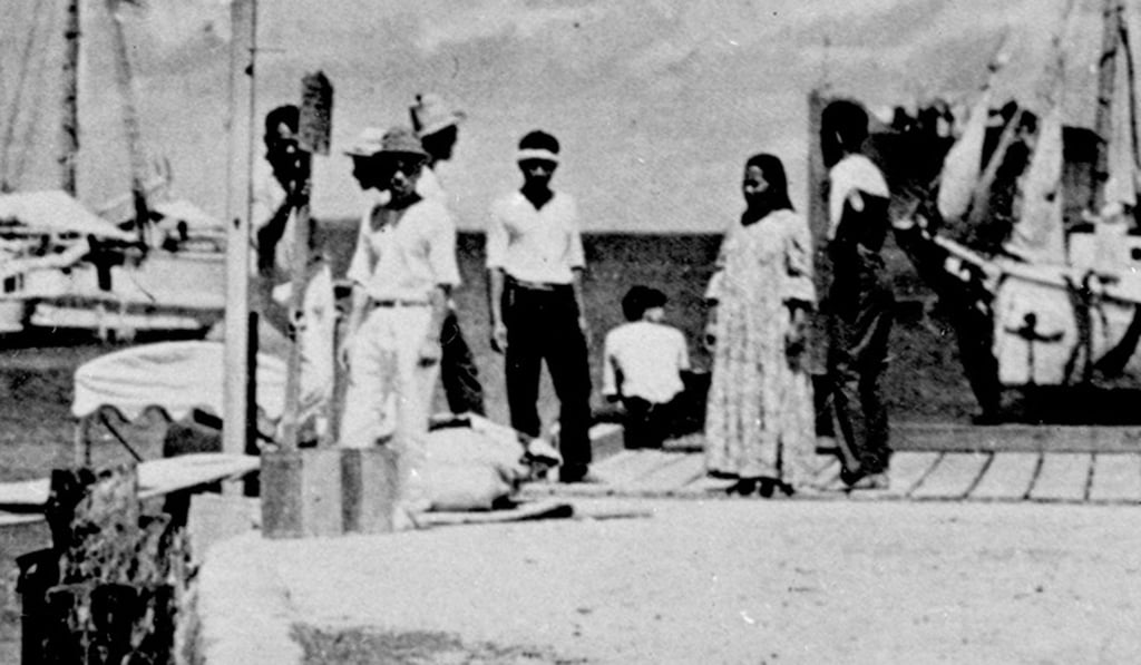 Some exerts suggest that the woman in the centre of this photo, seated on a wharf at Jaluit in the Marshall Islands, is Amelia Earhart, and the man standing on the far left is her navigator, Fred Noonan. Photo: A+E Networks Some exerts suggest that the woman in the centre of this photo, seated on a wharf at Jaluit in the Marshall Islands, is Amelia Earhart, and the man standing on the far left is her navigator, Fred Noonan. Photo: A+E Networks