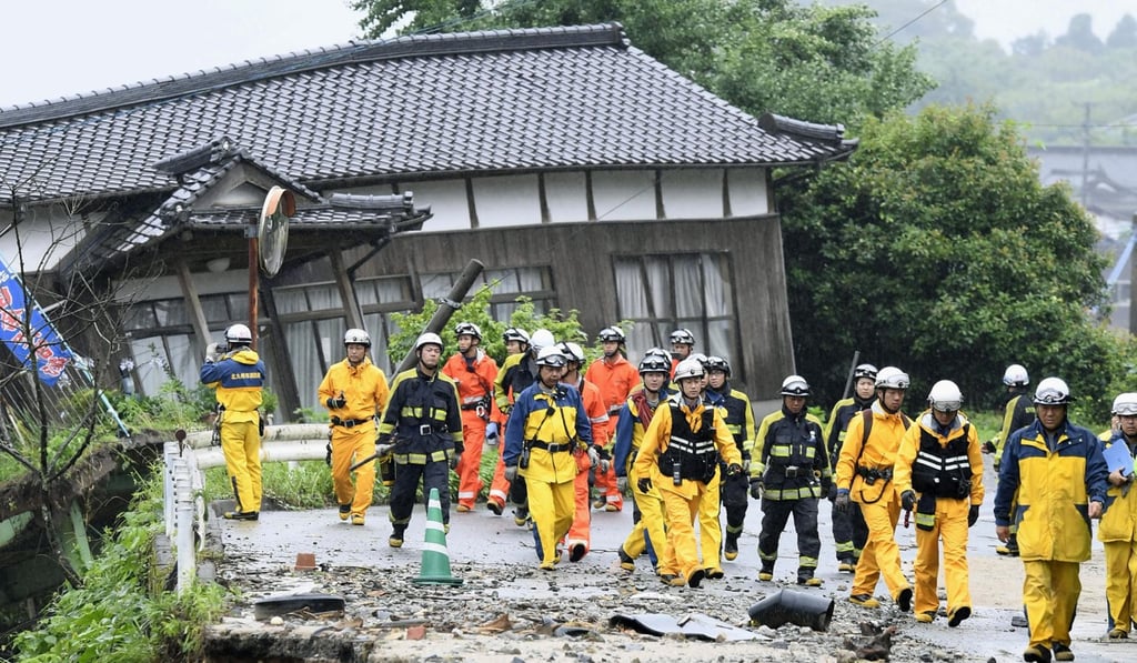Firefighters walk on the damaged road following the flooding caused by heavy rain in Asakura. Photo: Kyodo Firefighters walk on the damaged road following the flooding caused by heavy rain in Asakura. Photo: Kyodo
