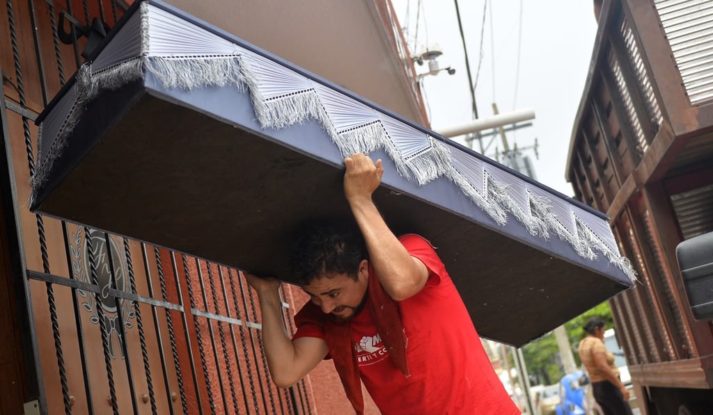 A funeral parlour worker carries a coffin for one of the 28 inmates killed in a riot at the Las Cruces prison. Photo: AFP