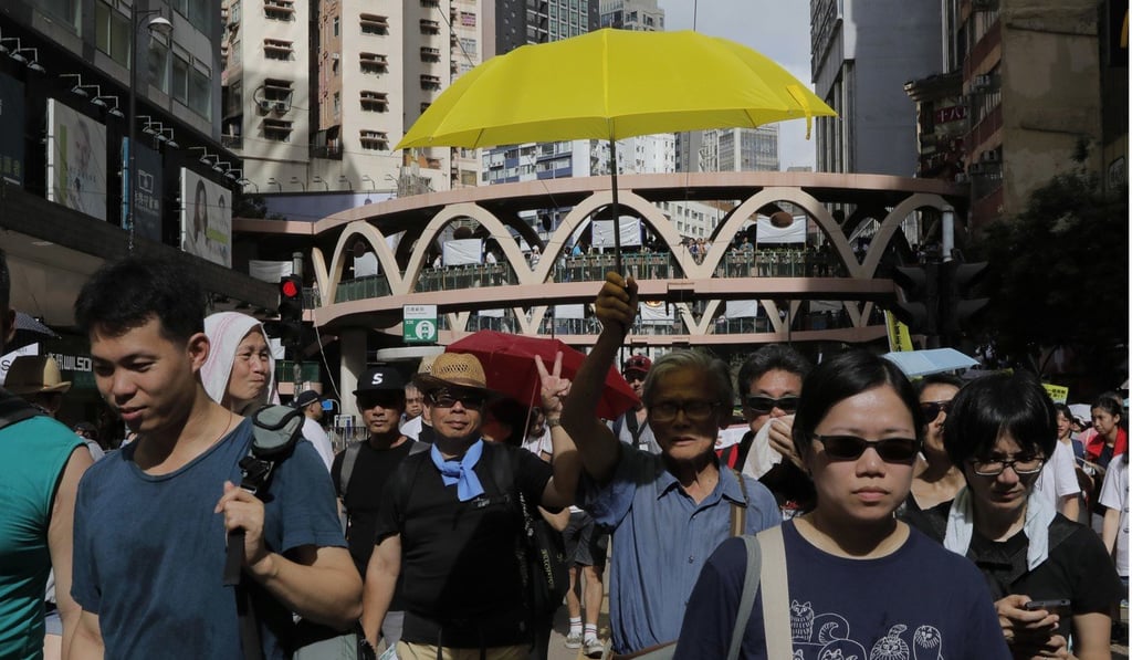 A protester carries a yellow umbrella, a symbol of the 2014 Occupy Central pro-democracy protests, as Hongkongers march on the streets during the annual July 1 rally in Hong Kong. Photo: AP
