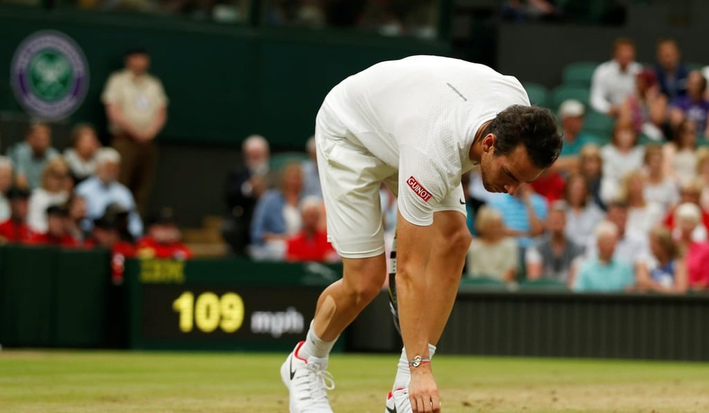 Adrian Mannarino replaces a divot on Centre Court. Photo: Reuters