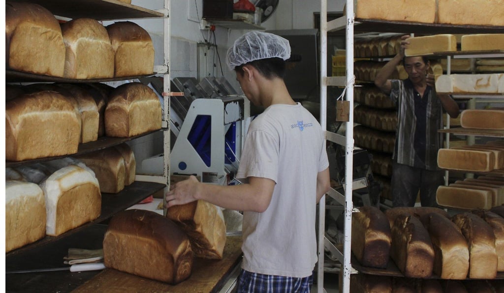 A baker slices burnt tops off loaves of bread at Sweetlands Confectionery & Bakery in Singapore. Photo: Juliana Loh