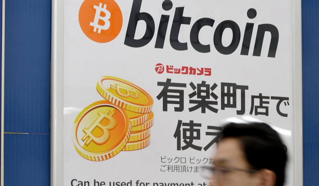 This picture taken on April 7, 2017 shows a man walking past a signboard informing customers that Bitcoin can be used for payment at a store in Tokyo. Photo: AFP