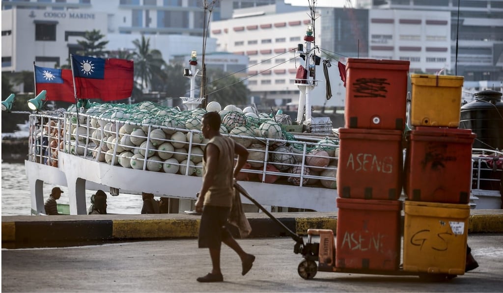 A dock worker pulls crates past the Taiwanese fishing longliners at the Jurong Fishery Port in Singapore. Photo: EPA