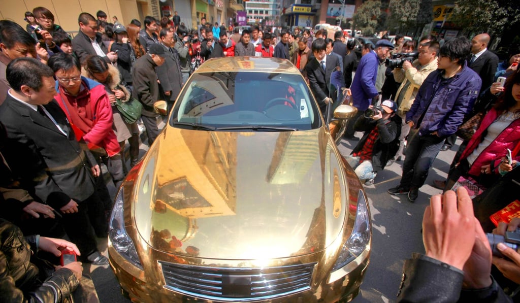 A crowd gathers to admire a gold-plated Infiniti sports car on display outside a jewellery store in Nanjing, Jiangsu province. Photo: AFP