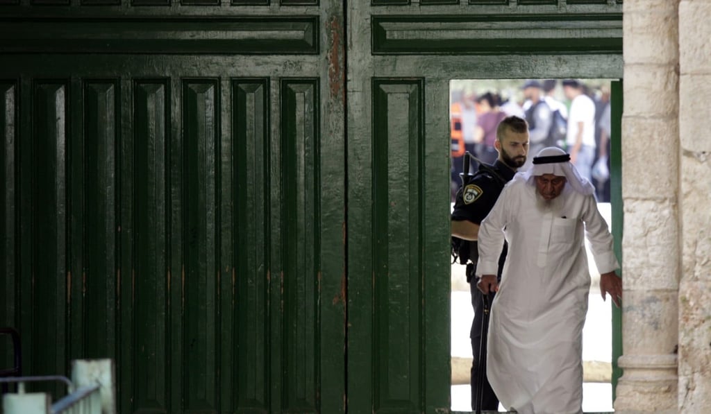 An Israeli police officer stands guard as a Muslim man walks out of the al-Aqsa Mosque compound. Photo: AP