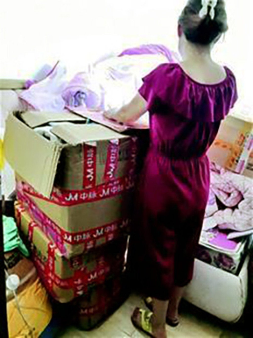 Li stands beside a tower of boxes of unsold underwear. Photo: Handout Li stands beside a tower of boxes of unsold underwear. Photo: Handout