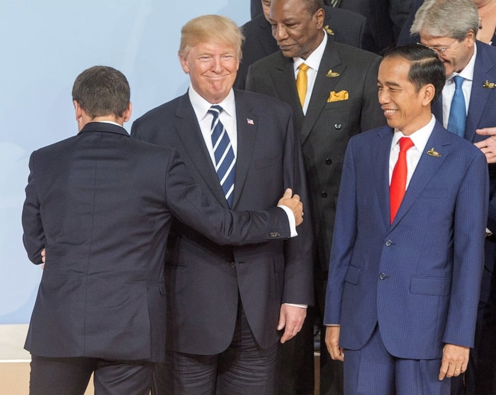 US President Donald Trump gets a hug from his French counterpart, Emmanuel Macron, as Indonesian President Joko Widodo looks on, as G20 leaders gather for a photo on the first day of their summit in Hamburg, on July 7. Photo: AP