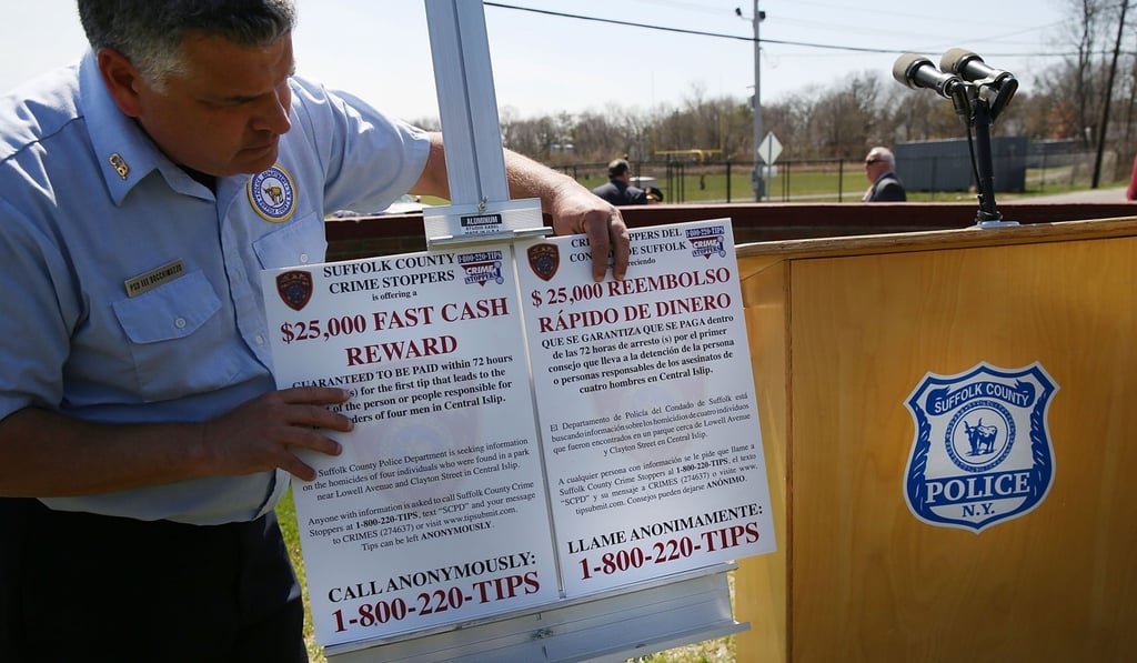 A city offical holds a notice at a news conference offering a US$25,000 “fast cash reward” for information that leads to an arrest in the killings of four men on April 13, 2017 in Central Islip, New York. Photo: AFP