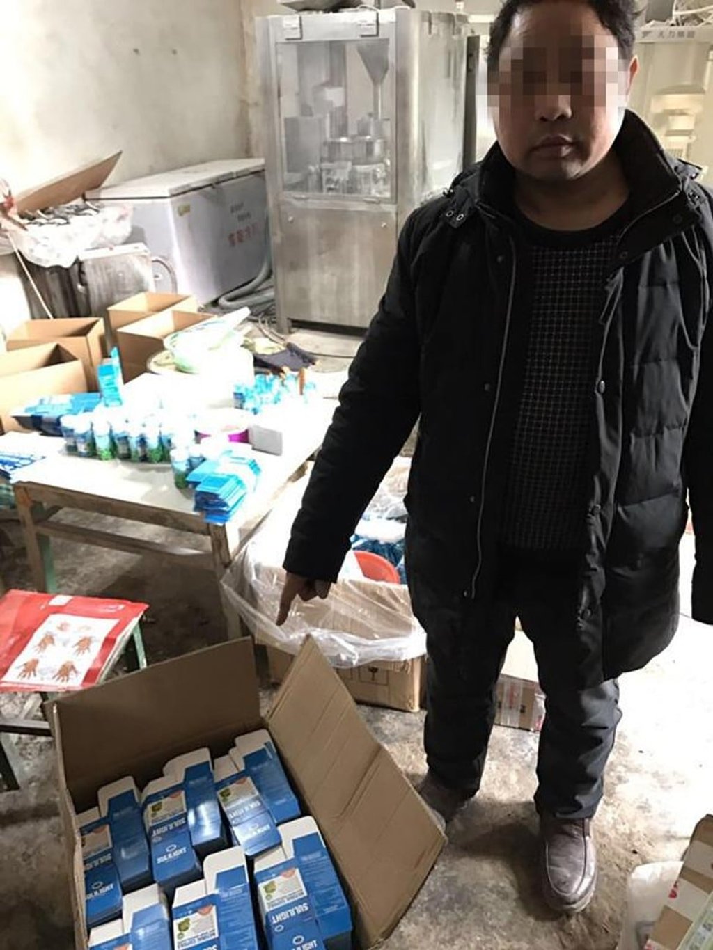 One of the suspects points to a box of the illicit products. Photo: Handout