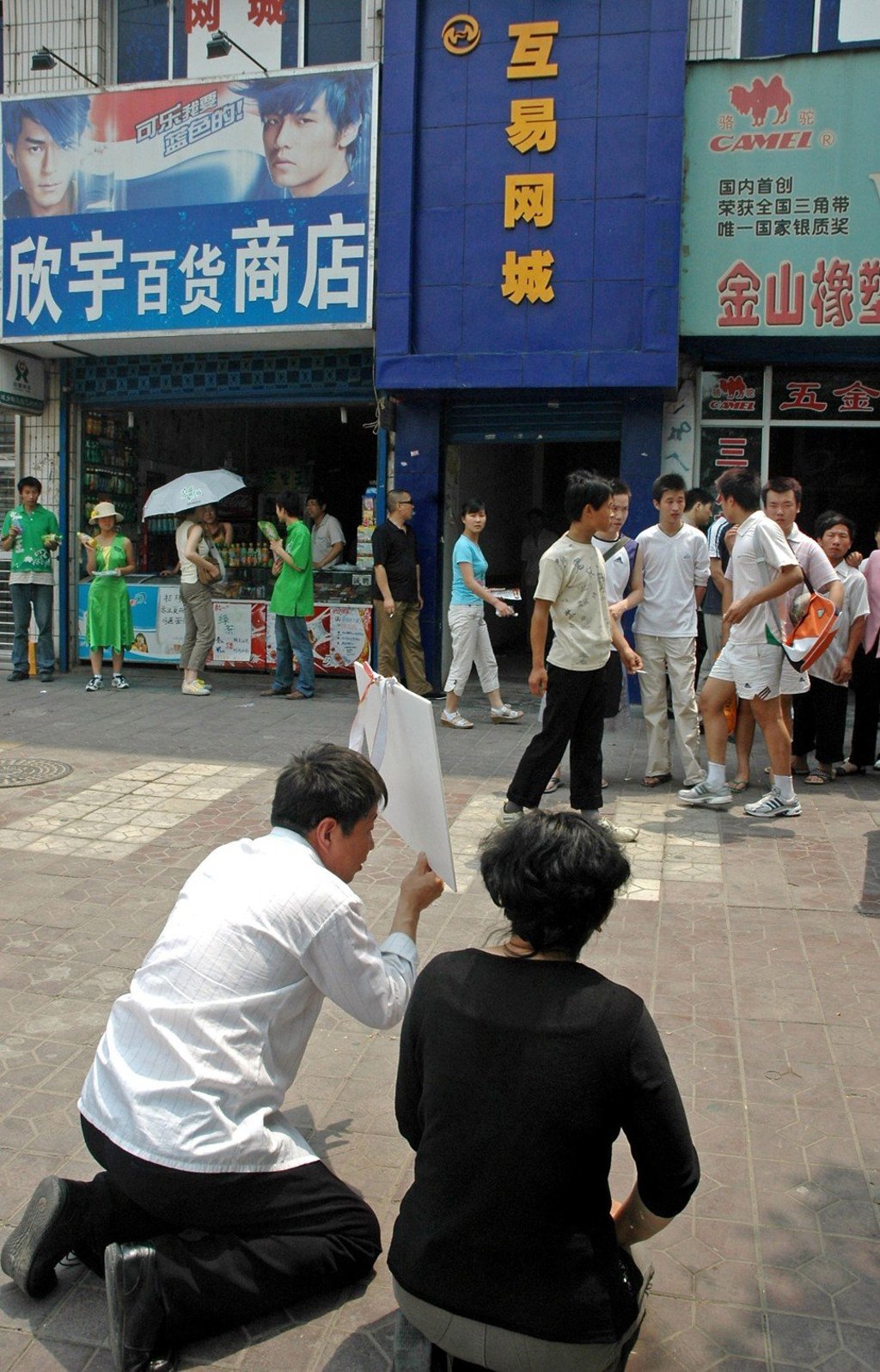 A man and his wife go down on their knees outside an internet cafe as they beg their son to go home, after he stole money to play internet games, in Xian, Shaanxi province, in 2006. Photo: AFP