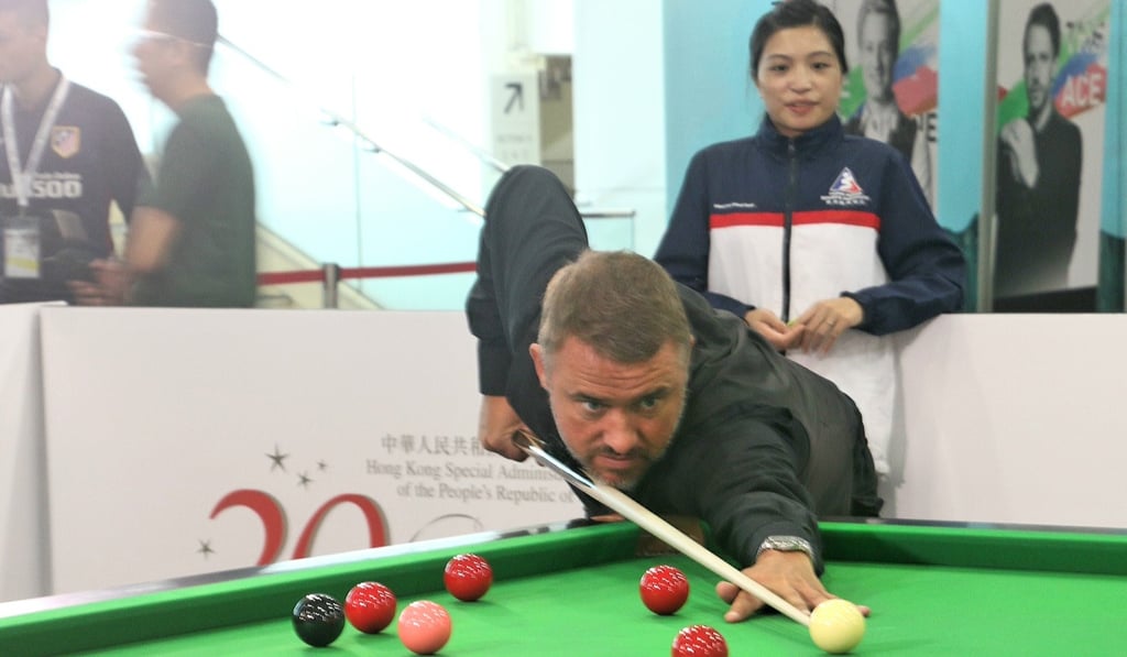 Stephen Hendry makes a pot while Katrina Wan looks on. Stephen Hendry makes a pot while Katrina Wan looks on.