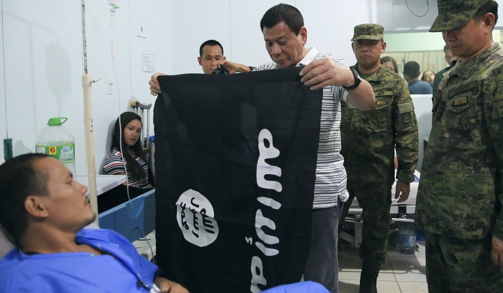 President Rodrigo Duterte holding a captured IS flag while visiting wounded soldiers in Cagayan de Oro. Photo: EPA
