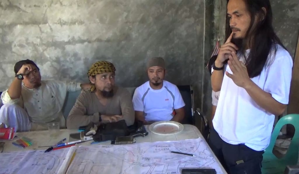 A screengrab from a video released by the Philippine Army of Abdullah Maute (right) looking at a map of Marawi, with Isnilon Hapilon (second from left), leader of hardline group Abu Sayyaf. Photo: AFP