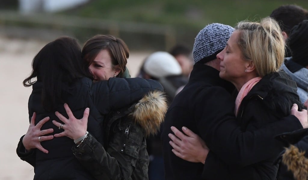 Family and friends comfort each other as they gather on Freshwater Beach following a candlelight vigil, where they threw hundreds of pink flowers into the ocean for Justine Damond. Photo: EPA