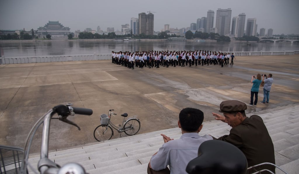 Tourists take photos by the Taedong river in Pyongyang. Photo: AFP