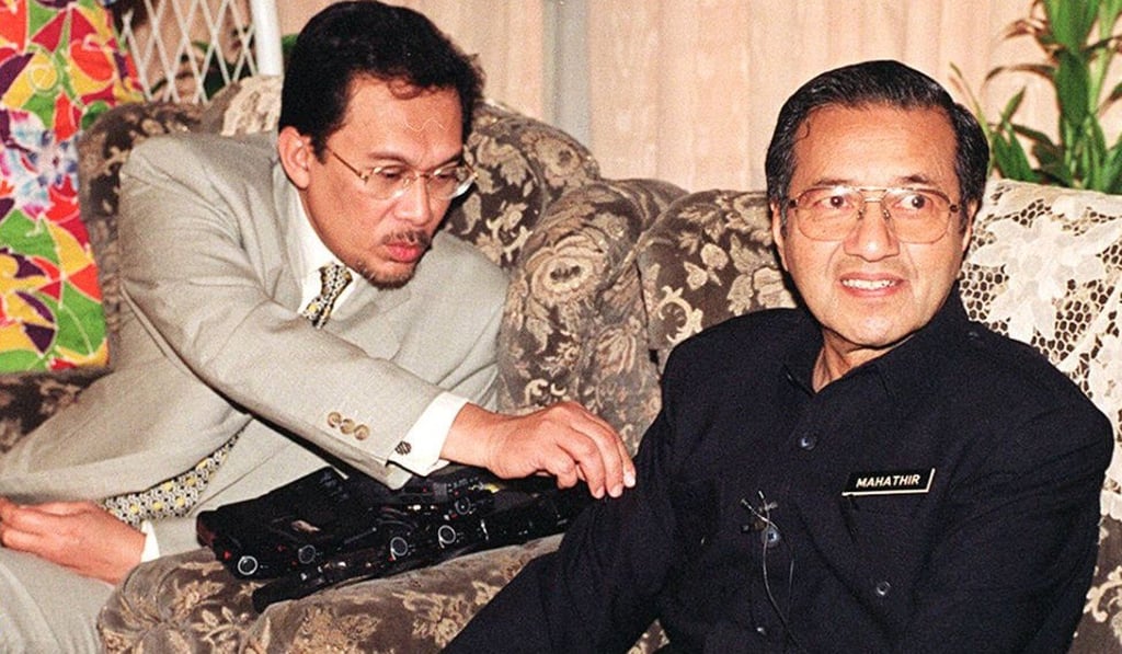Then Malaysian deputy prime minister Anwar Ibrahim (left) flicks dust off prime minister Mahathir Mohamad’s sleeve during a press conference in February 1997. The pair fell out the following year over allegations of corruption and sodomy against Anwar, who was sacked by Mahathir. But they have now reunited to take on Najib. Photo: AFP