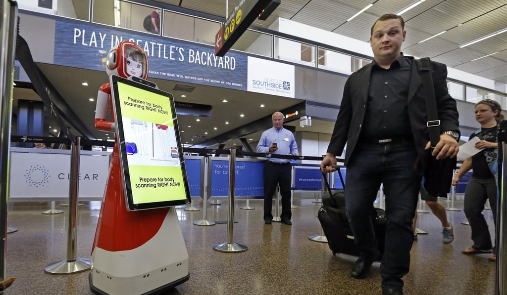 Airline passengers walk past a robot providing tips for getting through security faster during a pilot project as they head toward a security checkpoint at Seattle-Tacoma International Airport. Photo: AP Airline passengers walk past a robot providing tips for getting through security faster during a pilot project as they head toward a security checkpoint at Seattle-Tacoma International Airport. Photo: AP