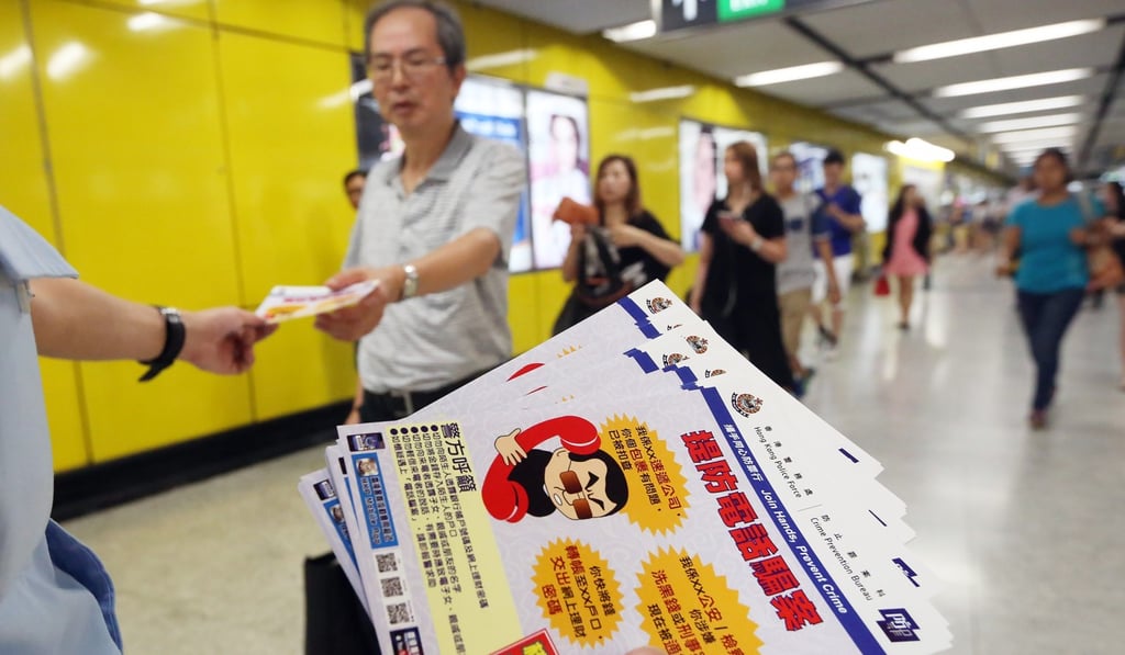 Police officers from the Crime Prevention Bureau give out leaflets at MTR stations to warn citizens about phone scammers, in August 2015. Photo: Sam Tsang