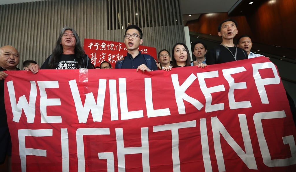The four carry a banner and chant their defiance. Photo: Edward Wong