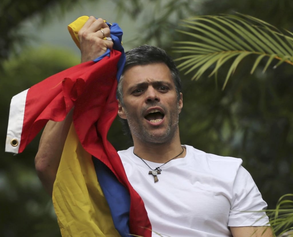 Venezuela's opposition leader Leopoldo Lopez holds a national flag as he greets supporters outside his home in Caracas. Photo: AP Venezuela's opposition leader Leopoldo Lopez holds a national flag as he greets supporters outside his home in Caracas. Photo: AP