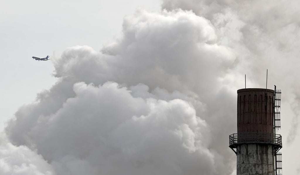 An airliner flies past steam and white smoke emitted from China Huaneng Group's Beijing power plant. Photo: AP