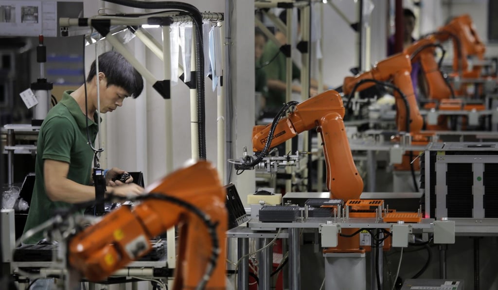 A human worker amid robot arms lined up at the Rapoo Technology factory in Shenzhen. Photo: AP
