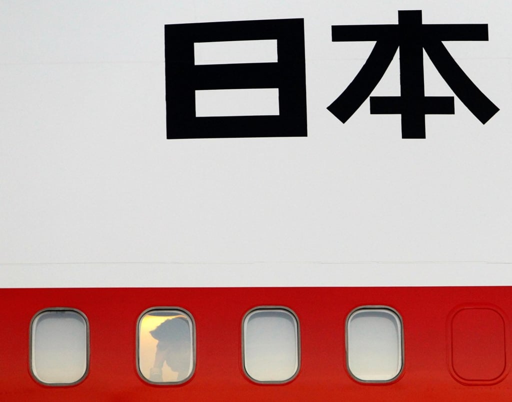 Japan’s Prime Minister Shinzo Abe is seen through a window of his plane as he arrives for an Apec summit in Bali, in October 2013. Photo: Reuters