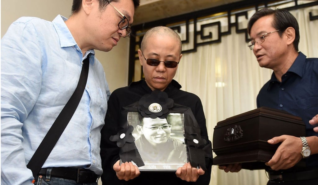 Liu Xia holds a portrait of Liu Xiaobo, while his brother Liu Xiaoguang (left) receives his ashes in Shenyang on July 15. Photo: AFP Liu Xia holds a portrait of Liu Xiaobo, while his brother Liu Xiaoguang (left) receives his ashes in Shenyang on July 15. Photo: AFP