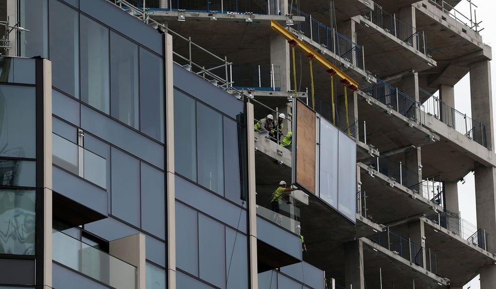 Workers move pieces of glass as they build residential flats on the Greenwich Peninsula construction site in London. Photo: Bloomberg