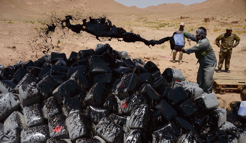 An Afghan policeman pours fuel over confiscated acetic acid, a key ingredient in heroin production, before setting it alight on the outskirts of Herat in July 11. Photo: AFP An Afghan policeman pours fuel over confiscated acetic acid, a key ingredient in heroin production, before setting it alight on the outskirts of Herat in July 11. Photo: AFP