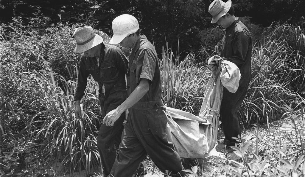 The body of one of Lam Kor-wan's victims is carried from the hillside above Tai Hang Road.