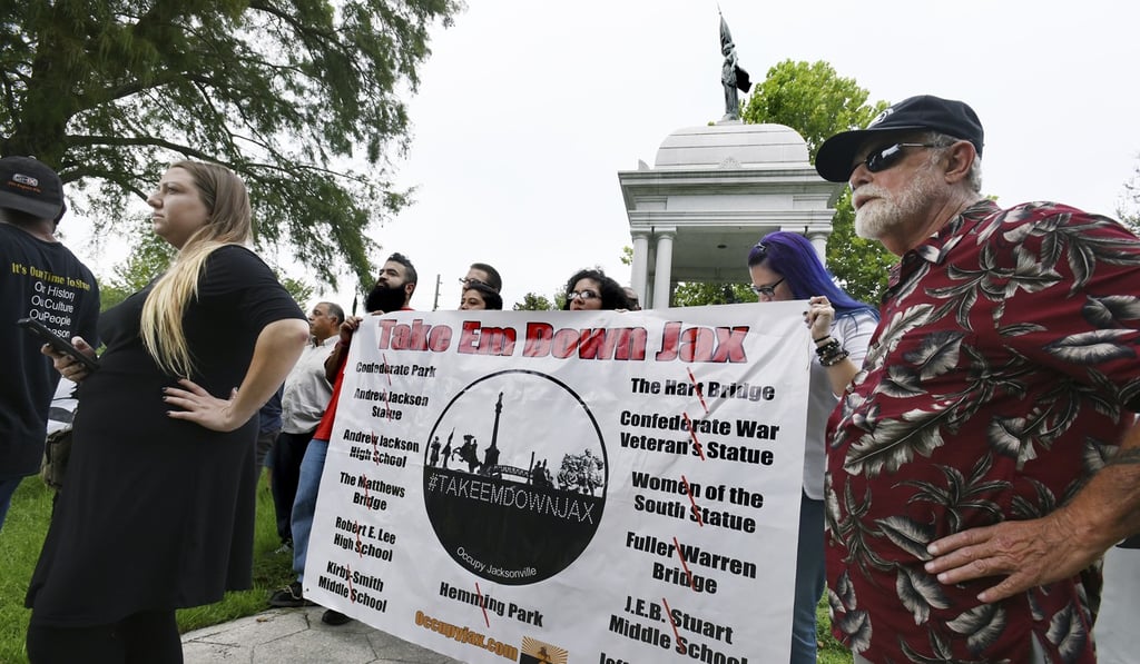 Members of the Take Em Down Jax organisation hold a banner with the list of offending confederate monuments as well as buildings and locations they want renamed during a rally in Jacksonville's Confederate Park in Jacksonville, Florida, on Tuesday. Photo: AP