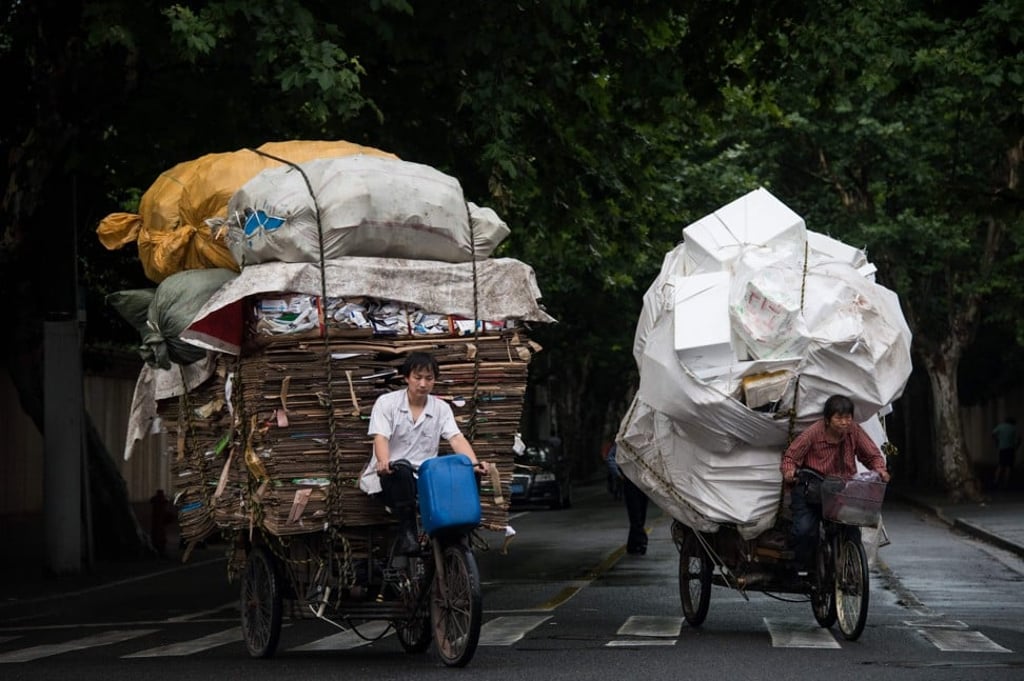 Waste collectors ride their loaded tricycles on the streets in Shanghai on June 20, 2016. Photo: AFP PHOTO