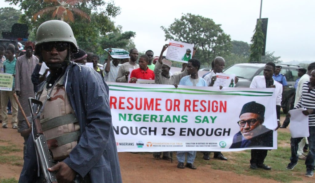 A policeman looks as protesters carry placards in the rain to demand that ailing President Mohammadu Buhari resume work or resign in Abuja, on August 7. File photo: AFP A policeman looks as protesters carry placards in the rain to demand that ailing President Mohammadu Buhari resume work or resign in Abuja, on August 7. File photo: AFP