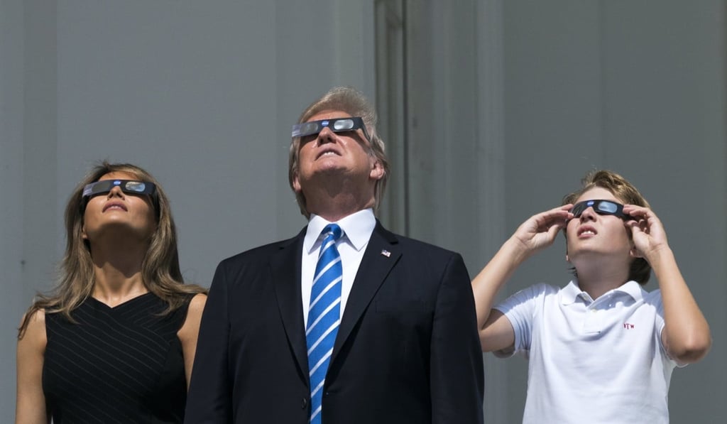 US President Donald Trump (centre), First Lady Melania Trump and their son, Barron Trump, view the solar eclipse from a balcony of the White House, wearing the proper protective glasses. Photo: EPA