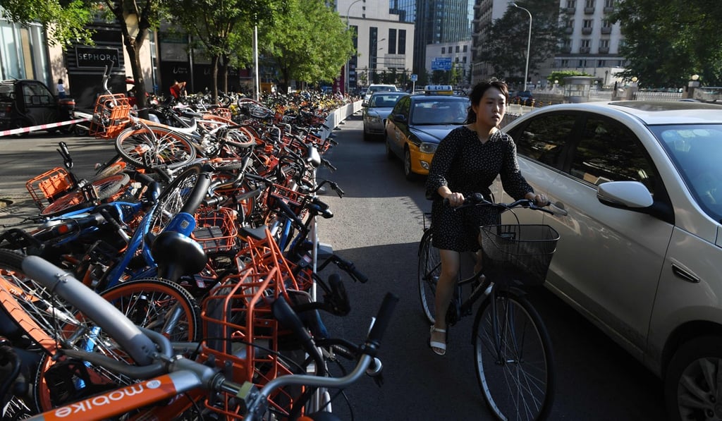 A woman rides in a car lane past a stack of shared bicycles blocking the cycle lane on a street in Beijing on August 3, 2017. Photo: AFP A woman rides in a car lane past a stack of shared bicycles blocking the cycle lane on a street in Beijing on August 3, 2017. Photo: AFP