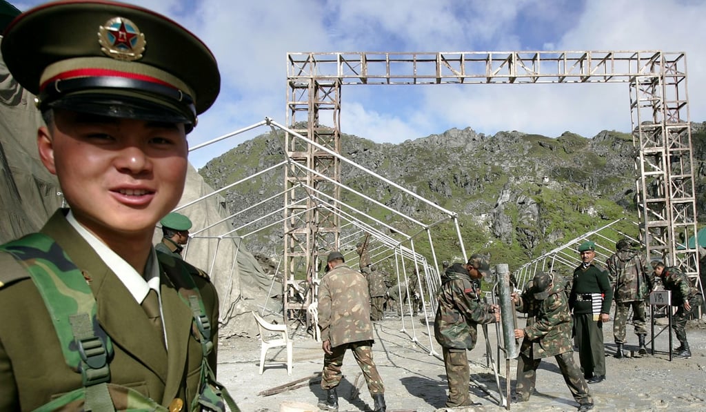 A Chinese soldier stands guard while Indian soldiers work at the Nathu La Pass in Tibet. Photo: AP