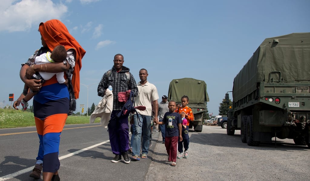 A group of asylum seekers walk down the street as they are escorted from their tent encampment to be processed at Canada Border Services in Lacolle, Quebec, on August 11. Photo: Reuters