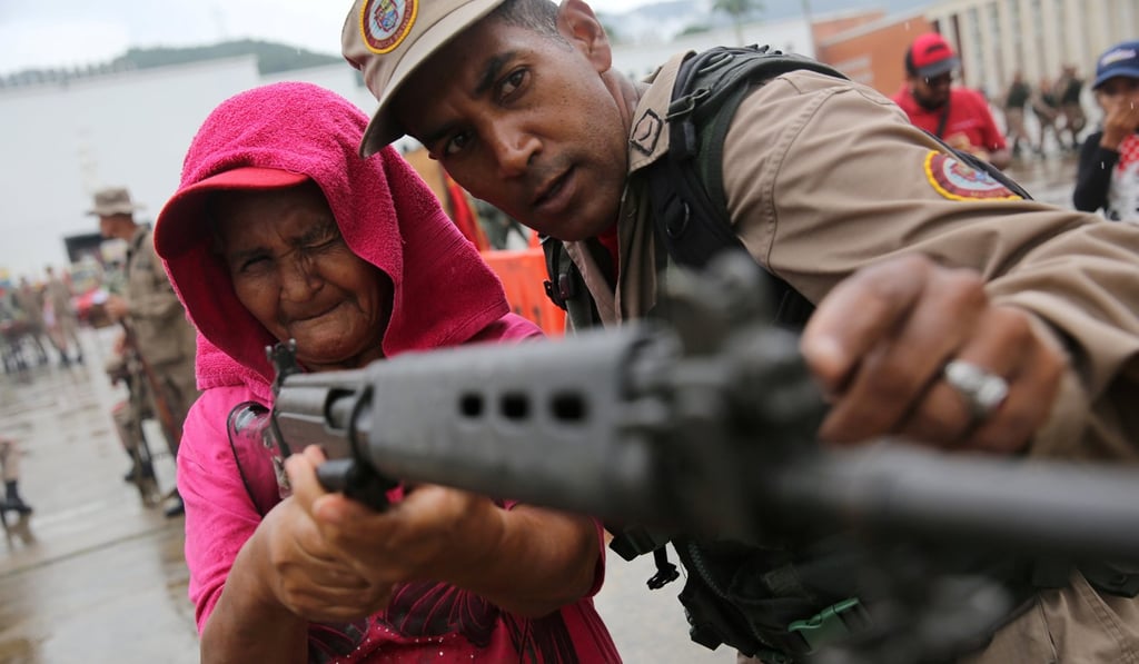 A member of the Militia of the National Bolivarian Armed Forces teaches a woman how to use a rifle during a military exercise in Caracas. Photo: Reuters
