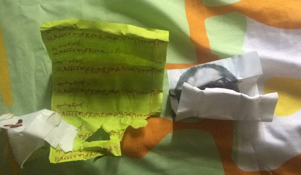 The talisman found by a man in Singapore containing a picture of himself, a piece of paper bearing Arabic script and some unidentifiable debris.