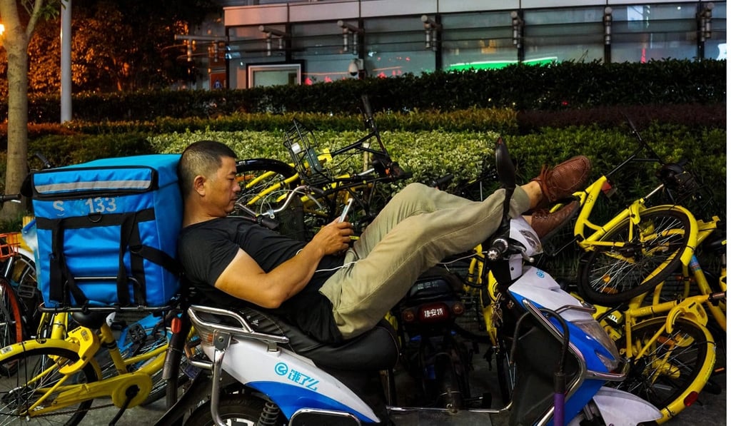 A Chinese food delivery man looks at his phone as he waits for orders in Shanghai on August 15, 2017. Photo: AFP