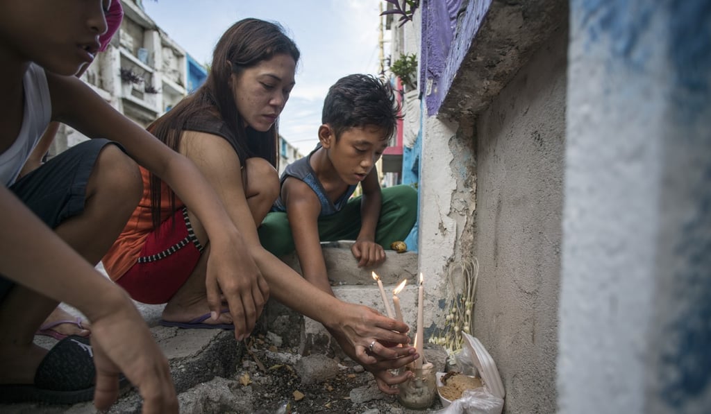 Susan Aguirre lights candles at the apartment tomb of her mother, Virginia, in Manila’s Pasay City Public Cemetery.