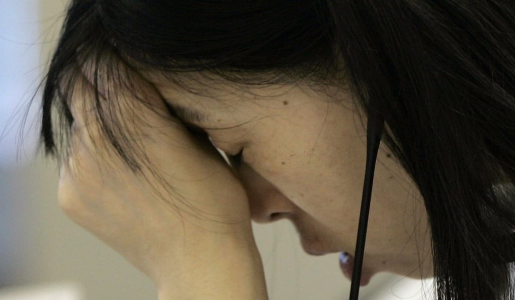 A call centre officer presses her hand to her forehead at an online brokerage company in Tokyo on October 23, 2008. Photo: Reuters