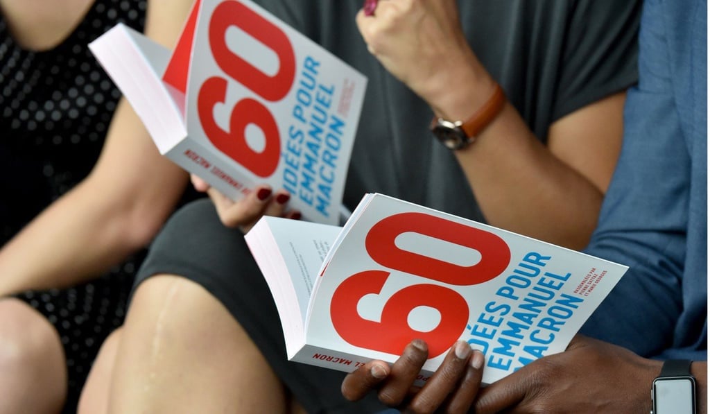 Participants read the book ‘60 ideas for Emmanuel Macron’, compiled from participants’ input during the Medef “summer university” meeting in Jouy-en-Josas on Wednesday. Photo: FP