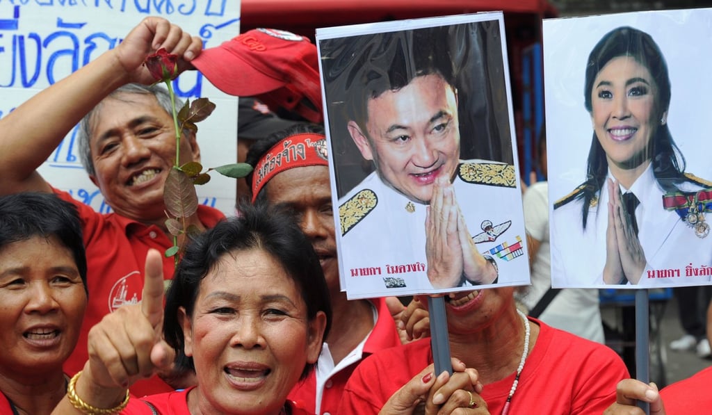 Red Shirt supporters hold pictures of fugitive former leader Thaksin Shinawatra and his sister Yingluck in Bangkok. Photo: AFP