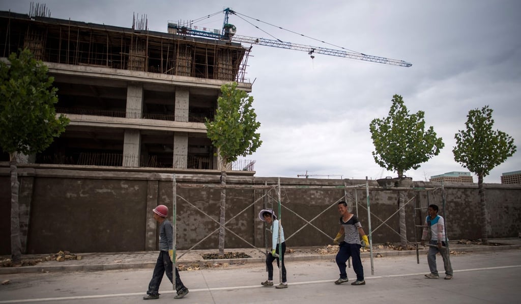 Workers carry scaffolding past a construction site at Kashgar’s Shenzhen City, a development financed by the southern Chinese city. Photo: AFP Workers carry scaffolding past a construction site at Kashgar’s Shenzhen City, a development financed by the southern Chinese city. Photo: AFP