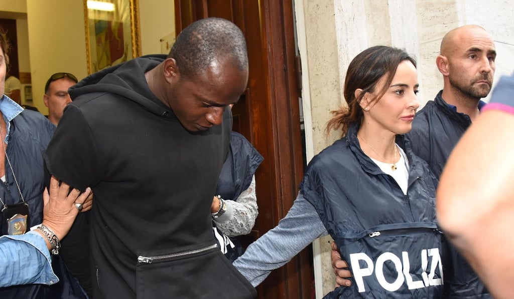A man identified as Congolese refugee Guerlin Butungu (left) is escorted by police officers after being arrested in Rimini. Photo: AP A man identified as Congolese refugee Guerlin Butungu (left) is escorted by police officers after being arrested in Rimini. Photo: AP