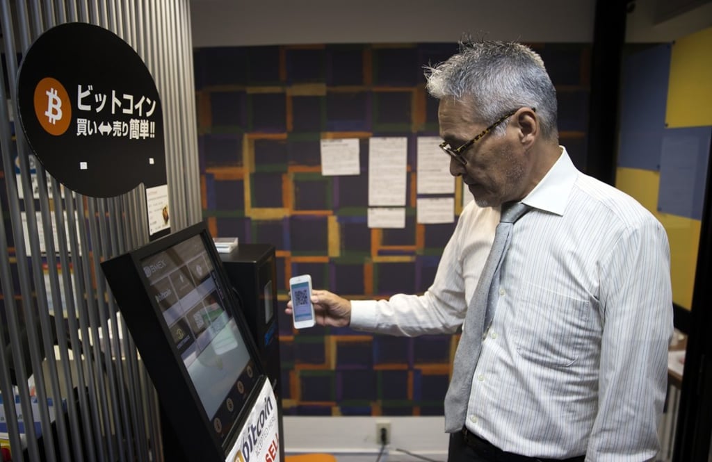 An employee uses a smartphone to demonstrate purchasing bitcoin from an automated teller machine at the Coin Trader bitcoin retail store in Tokyo, on August 30. Photo: Bloomberg